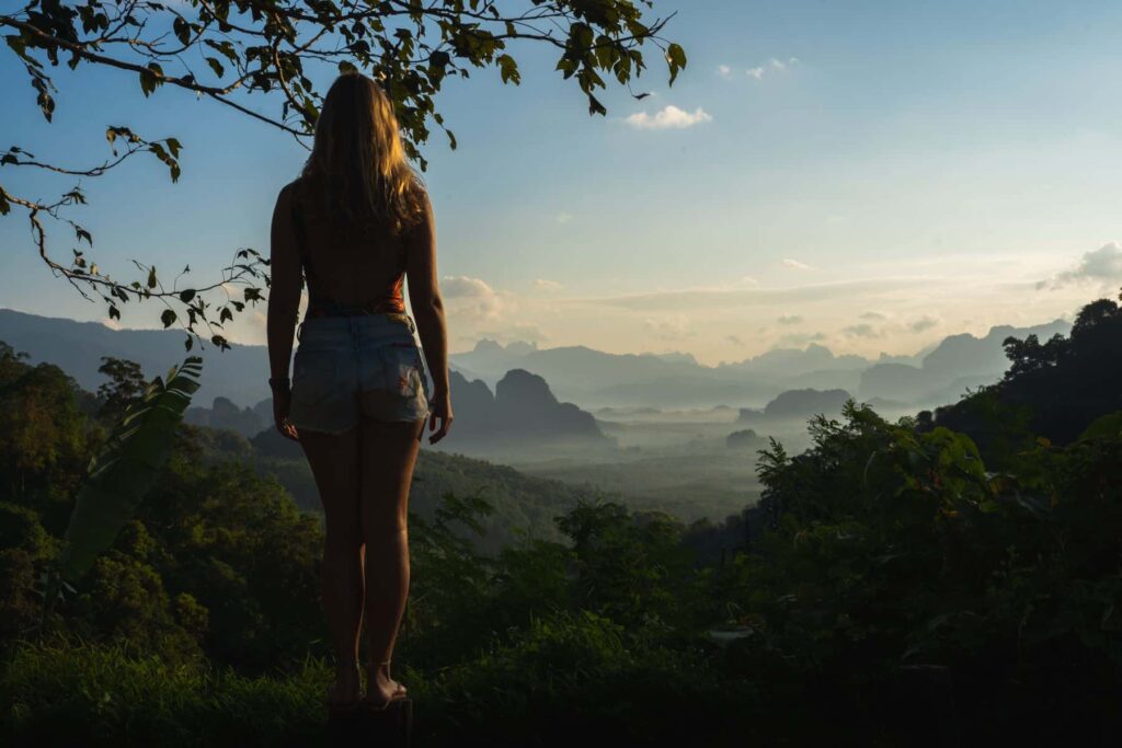 Femme contemplant le paysage brumeux de Khao Sok au lever du soleil depuis un point de vue panoramique accessible après avoir appris comment se rendre à Khao Sok